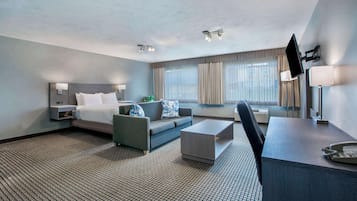 A hotel room with a bed, a sofa, a desk, and a TV.