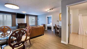 Hotelkamer met een zithoek, een sofa, een televisie en een badkamer, zichtbaar door een geopende deur.