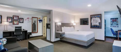 A hotel room with a bed, desk, chair, and a small sofa.