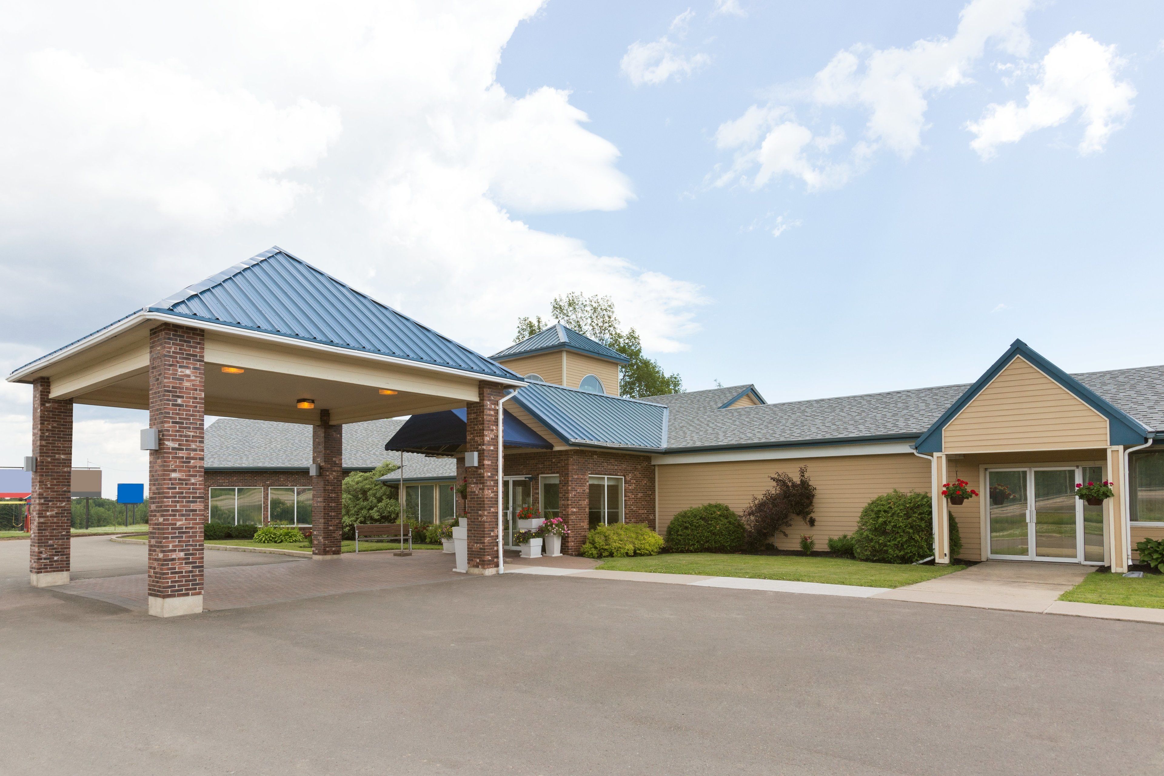 A building with a covered entrance, brick pillars, and a blue roof.
