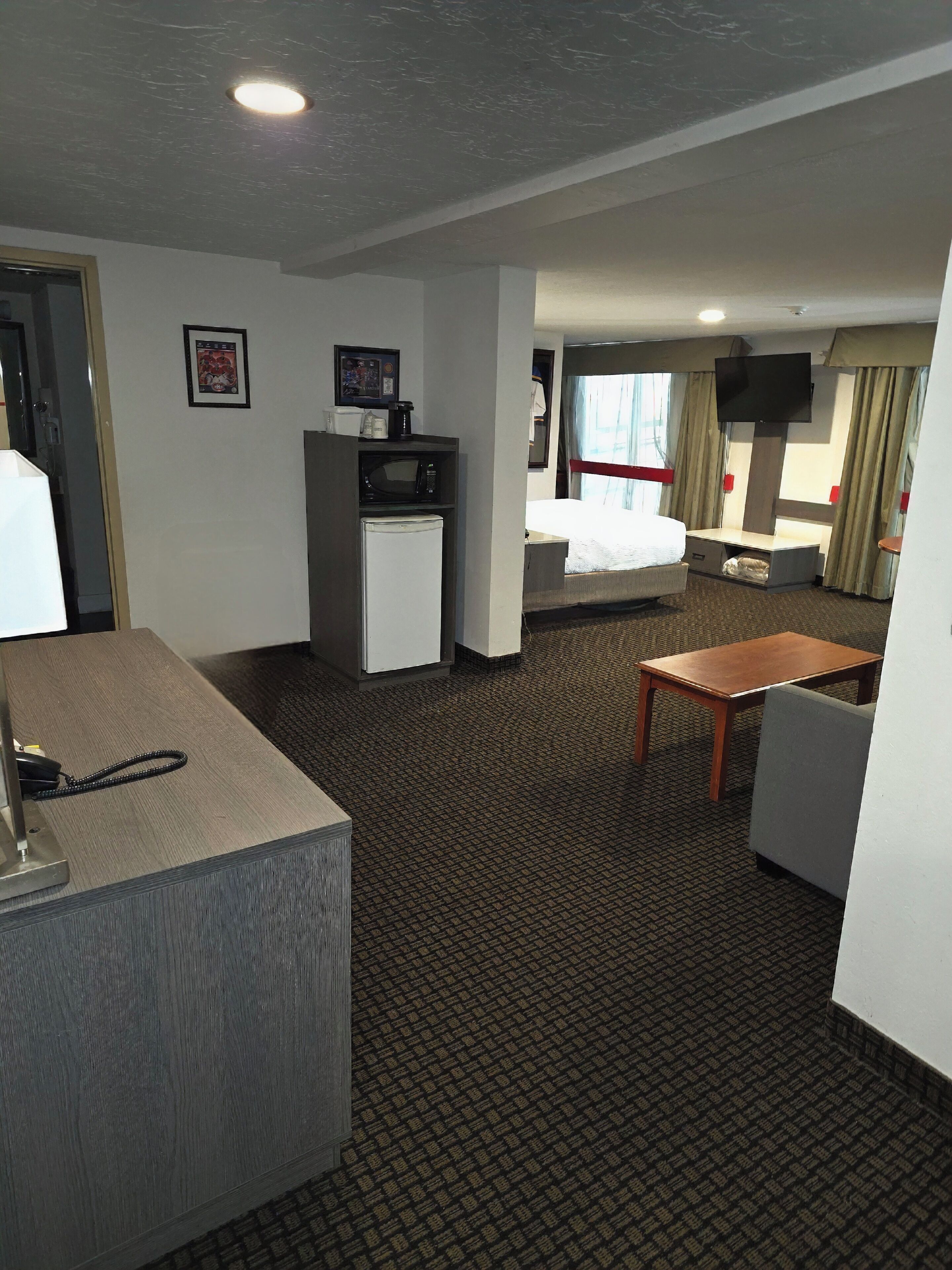 Una habitación de hotel con escritorio, cama, televisor, microondas y refrigerador.