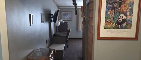 A hallway with a dining area, a framed wildlife poster, and a ceiling with a fur-like decoration.