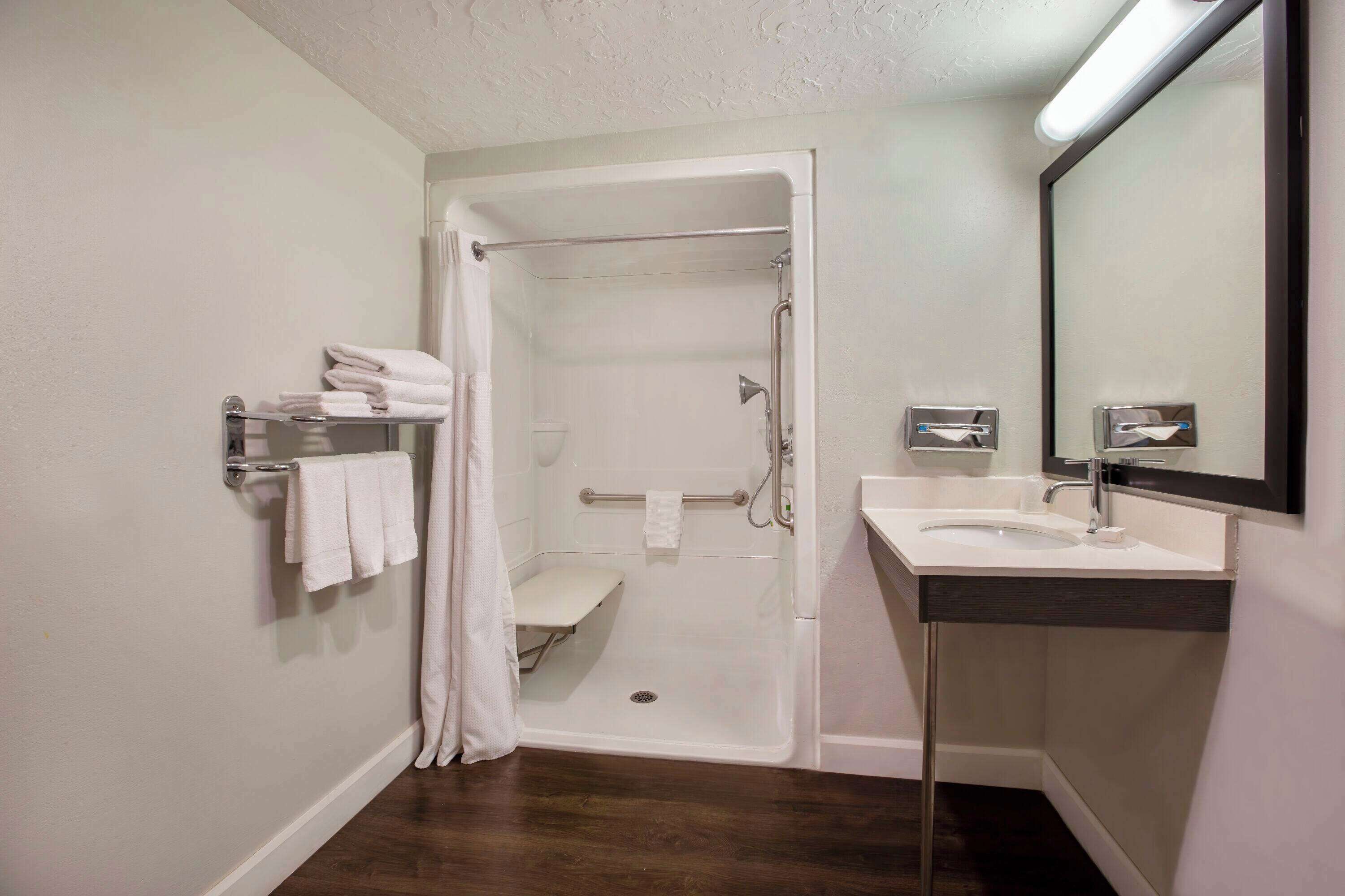A modern bathroom with a walk-in shower, a sink with a mirror, and a towel rack.