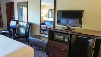 A hotel room with a bed, a desk with a telephone, a television, a microwave, and a refrigerator.