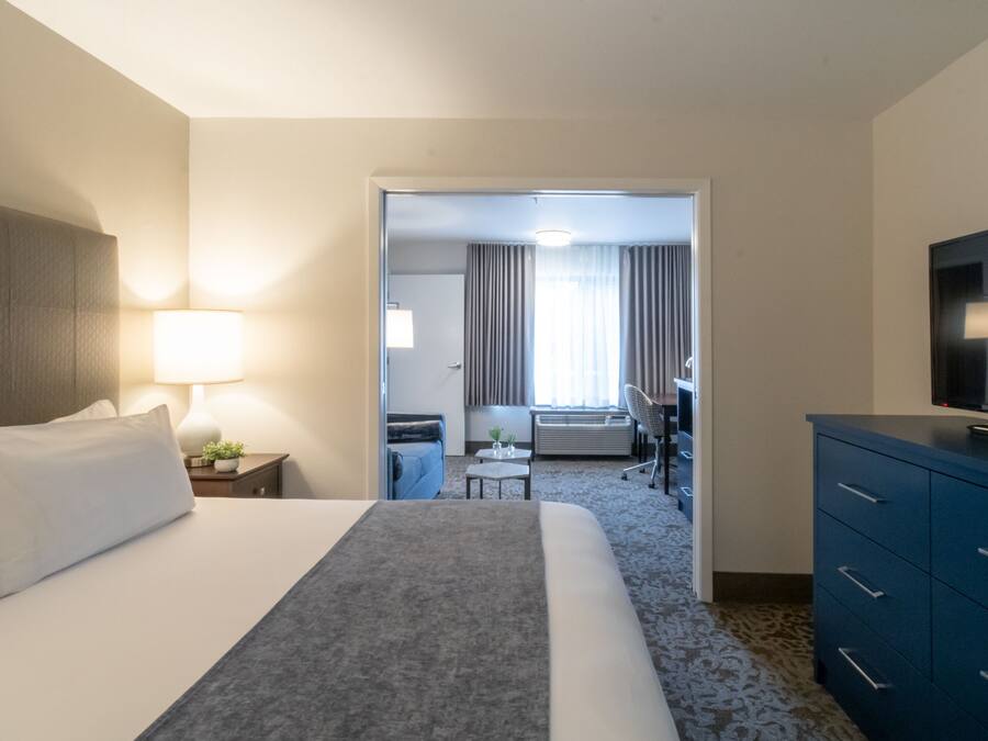 Una habitación de hotel con una cama, un escritorio, una silla, un televisor y un aparador.