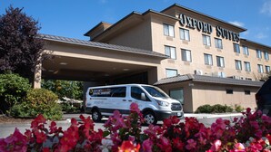 A hotel with a modern design, a covered entrance, and a van parked in front. - Oxford Suites Portland - Jantzen Beach (Portland)