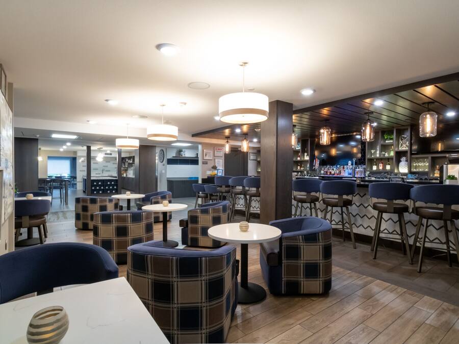 A modern restaurant interior with round tables, blue upholstered chairs, and pendant lighting.