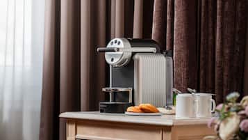 A coffee machine on a counter with a plate of croissants and a mug.