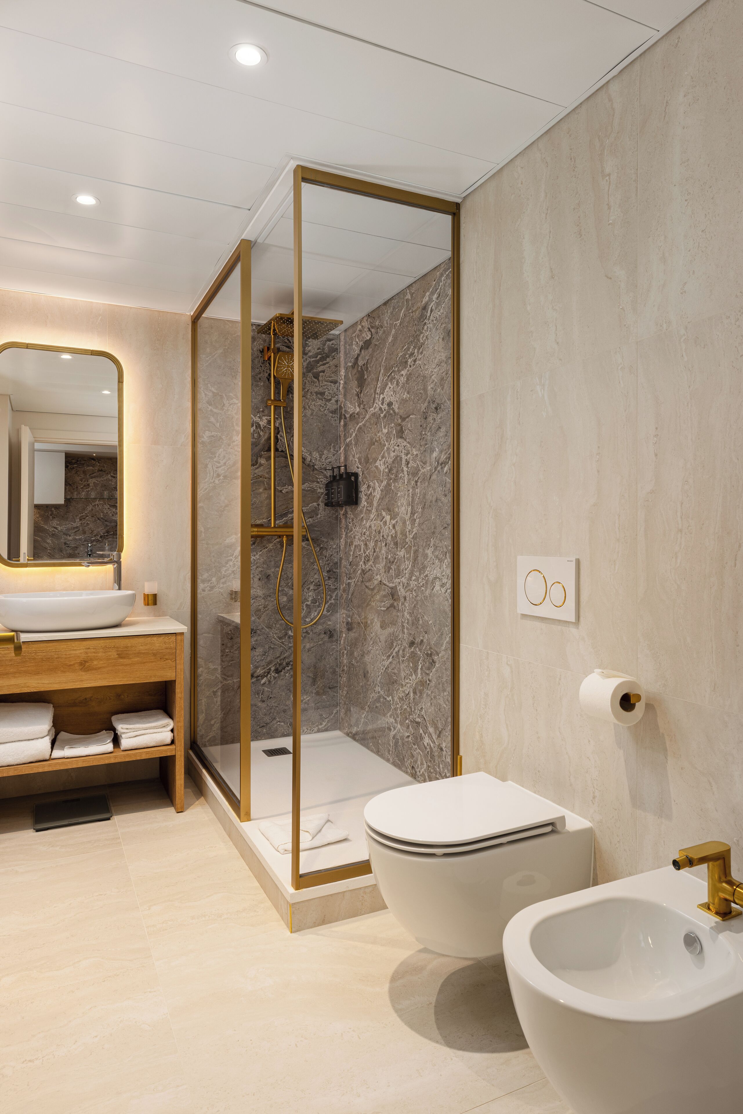 Un baño moderno con pared de mármol, ducha con cerramiento de vidrio, tocador de madera y dos lavamanos.