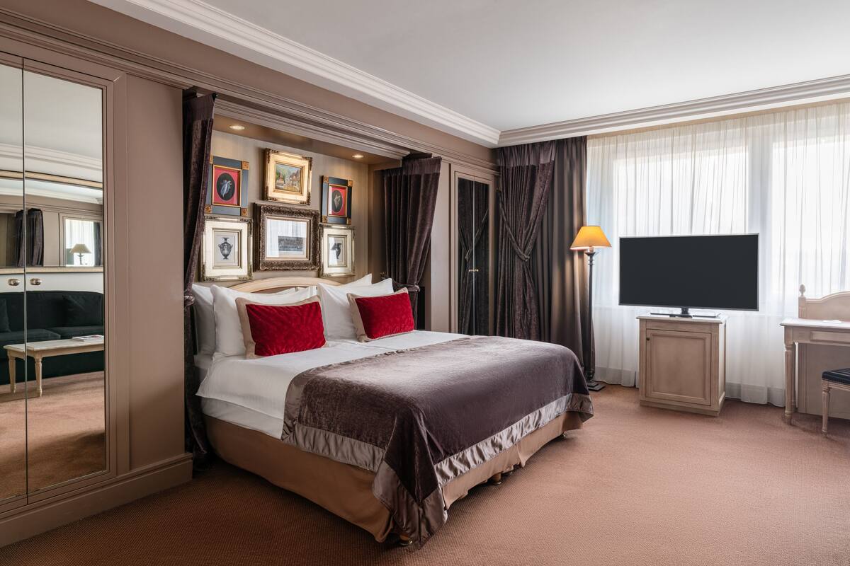 Hotellihuone, jossa on suuri sänky, televisio, työpöytä ja vaatekaappi.