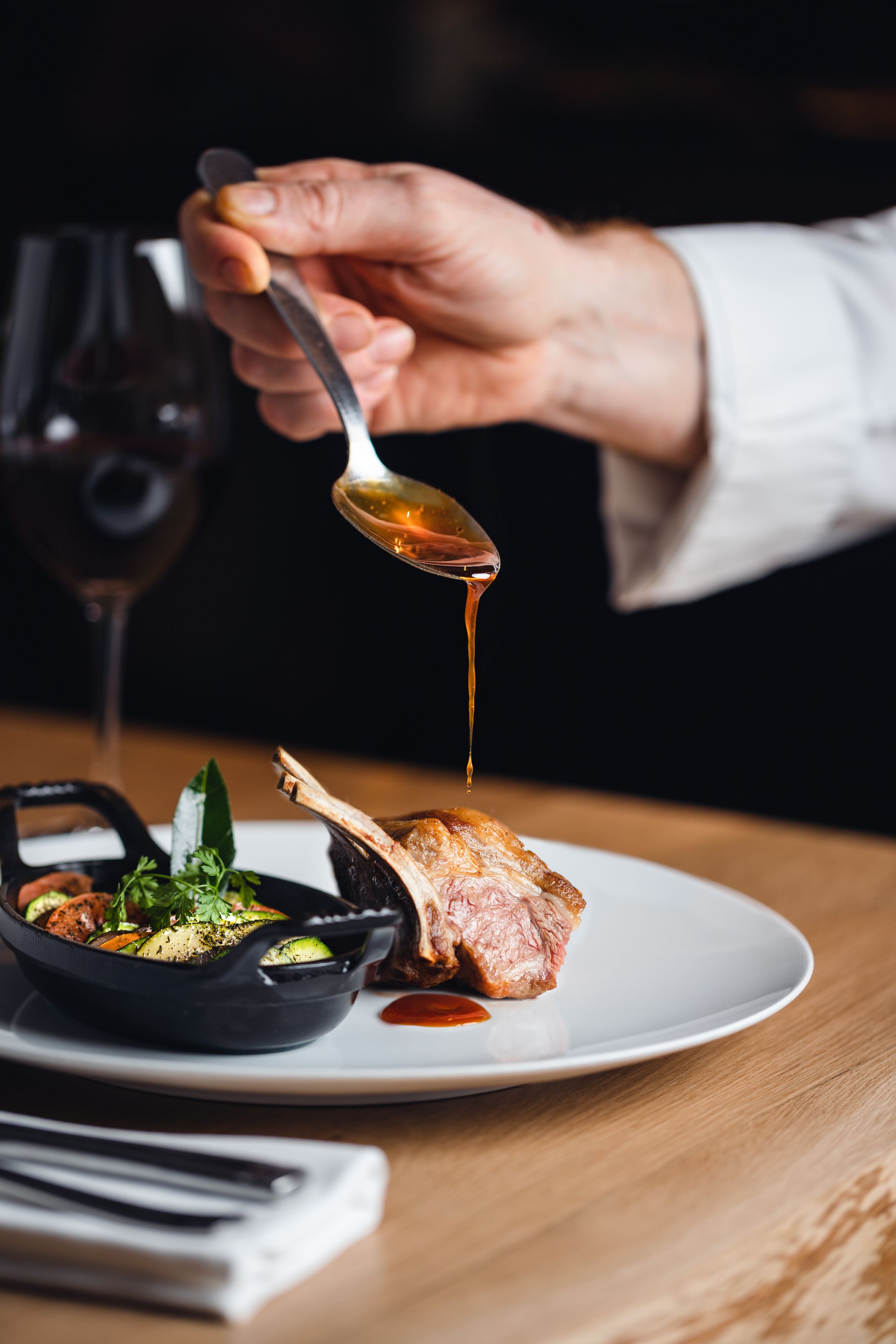 Una persona sirviendo un plato con una cucharada de salsa.