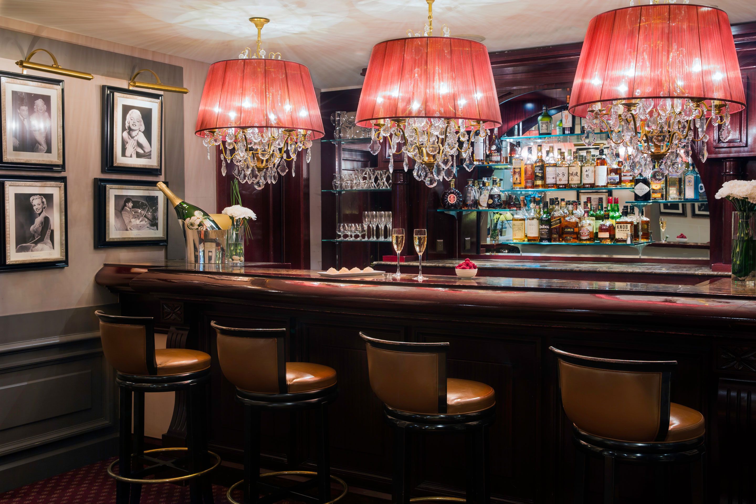 A bar area with three red lamps, a bar counter, and multiple stools.