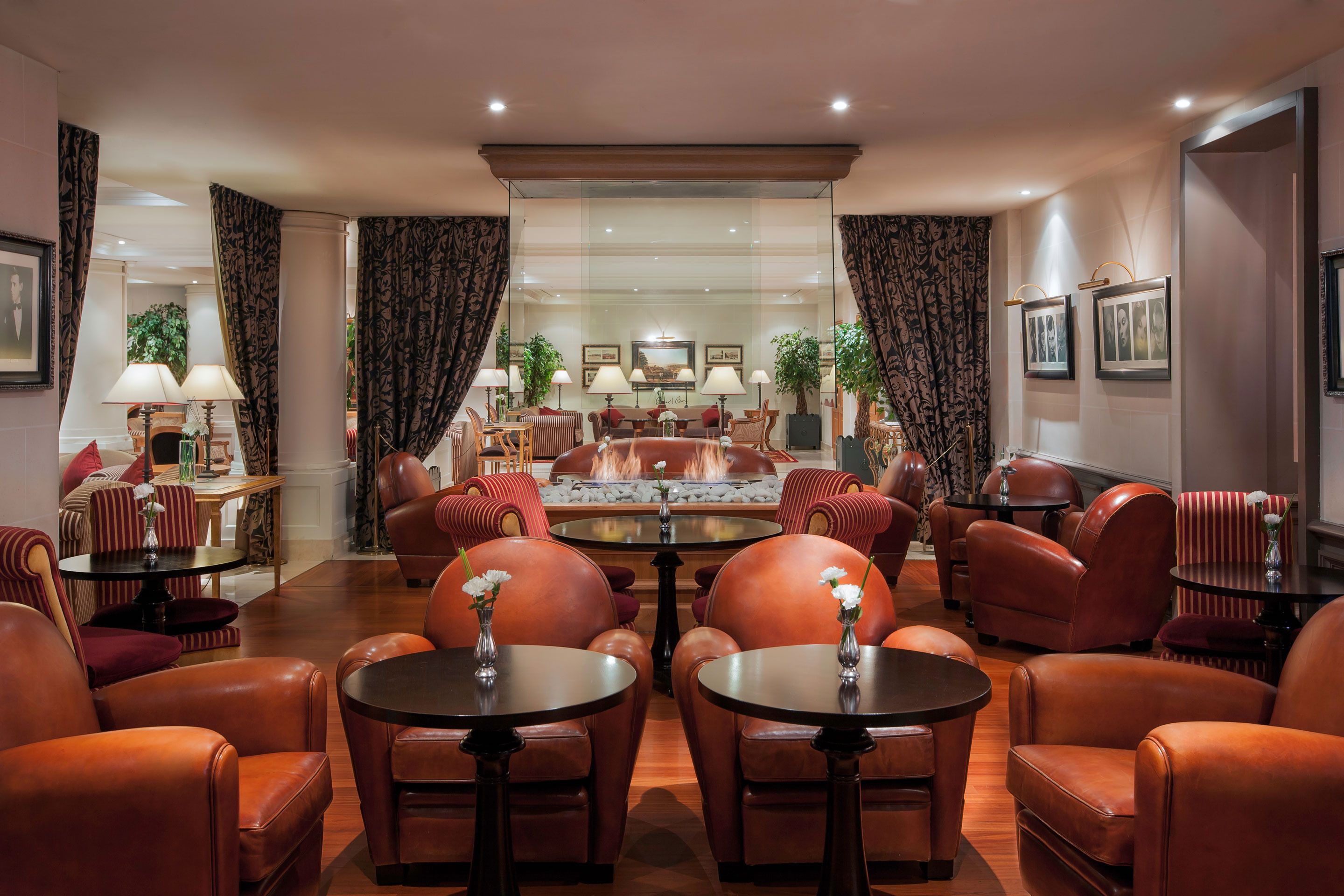 A spacious lounge area with leather seating, a central fireplace, and a dining table.