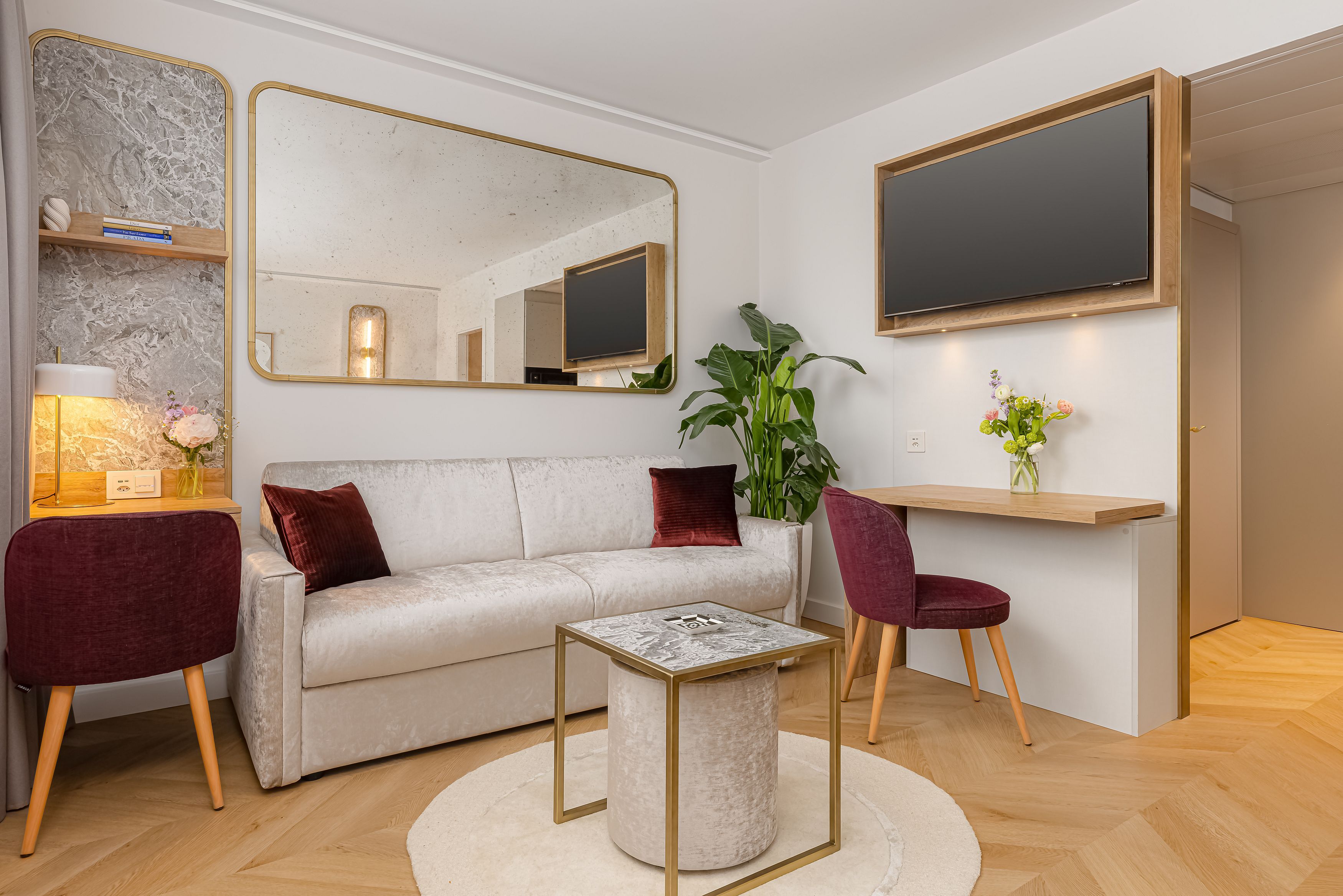 A modern living room with a sofa, a coffee table, a TV, and a plant.