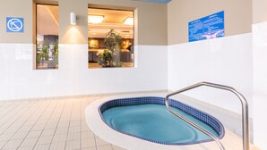 Una piscina con una escalera metálica, un cartel de prohibido bañarse y un área de recepción visible a través de una puerta.