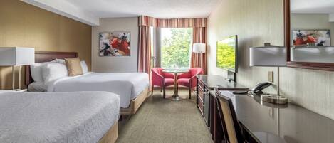 Habitación de hotel con dos camas, un escritorio, una silla, un espejo y una ventana con cortinas.