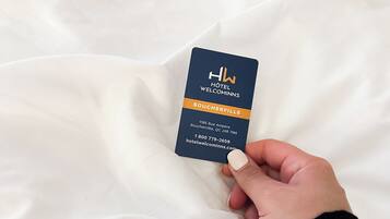 A hand holding a hotel business card for Hotel Welcomins Boucherville.