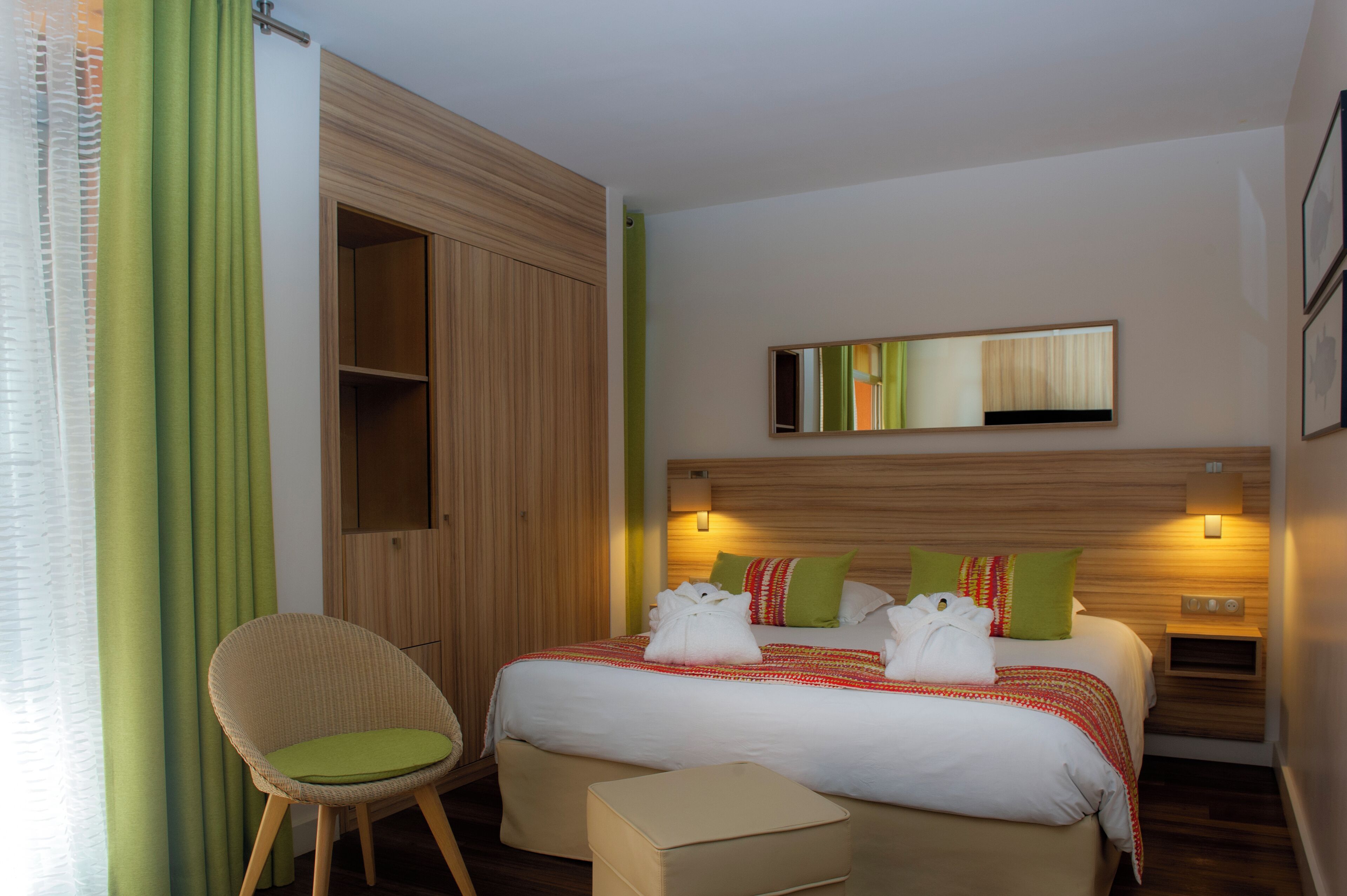 Une chambre d’hôtel comprenant un lit, une chaise, une table de chevet et une armoire.
