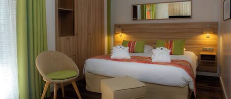 Une chambre d’hôtel comprenant un lit, une chaise, une table de chevet et une armoire.