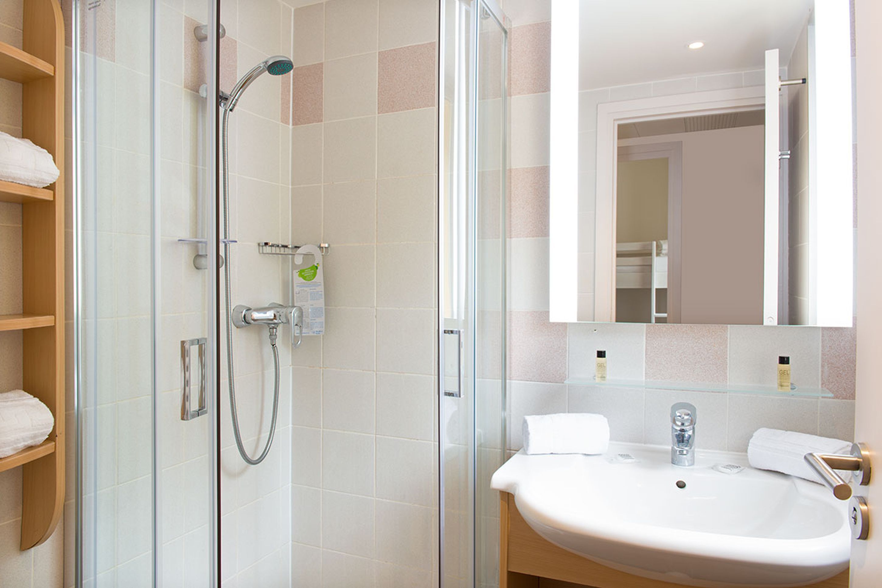 Un baño moderno con ducha de vidrio, lavamanos blanco y un espejo grande.