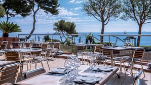 An outdoor dining area with tables set for two, overlooking a body of water. - Hôtel Vacances Bleues Delcloy (Saint-Jean-Cap-Ferrat)