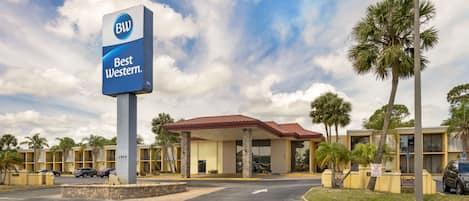 A hotel with a prominent 'BW Best Western' sign, featuring a red roof and a modern design.