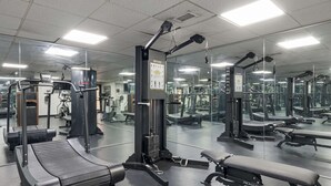 A gym with various exercise equipment, including treadmills, weight machines, and benches.