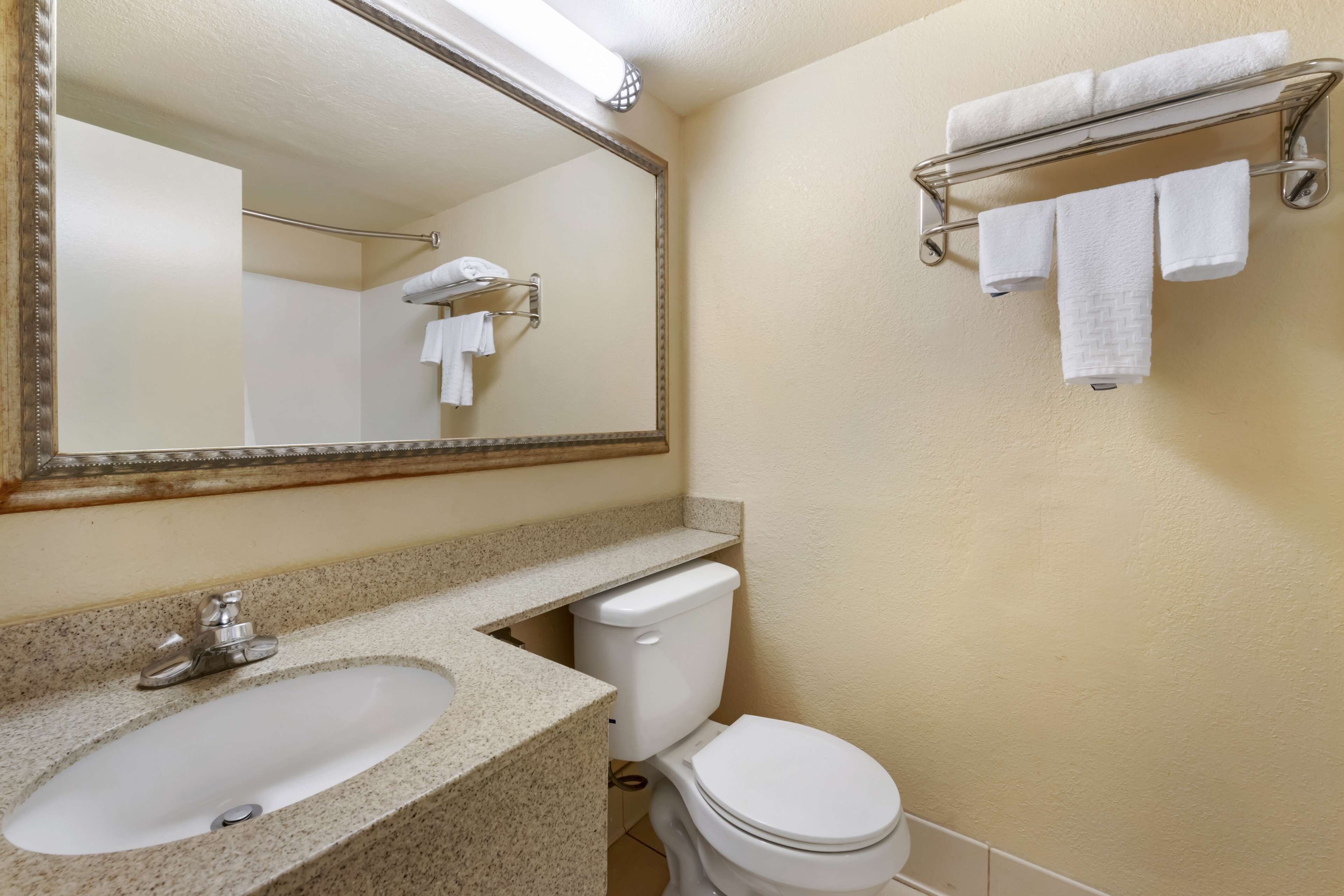Un baño con lavamanos, inodoro y toallero.