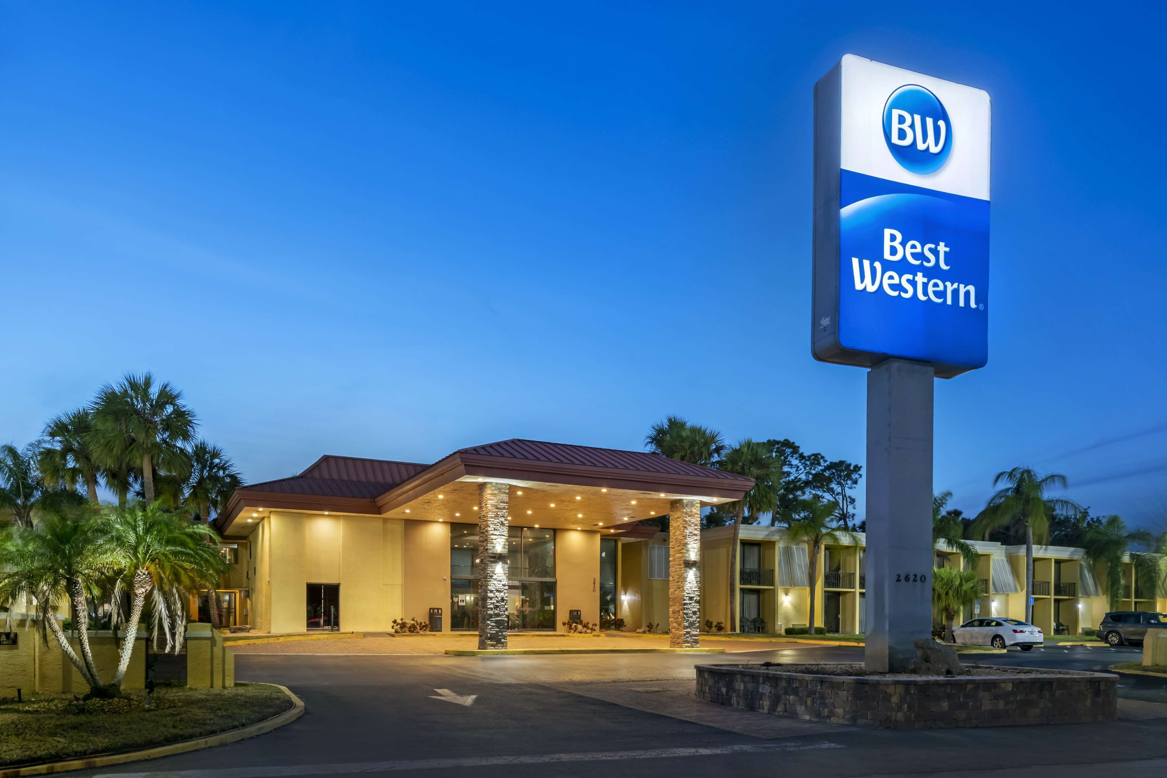 A hotel with a prominent 'Best Western' sign, a covered entrance, and palm trees.
