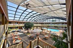 A spacious indoor area with a pool, multiple dining tables and chairs, and a large tree. - Best Western Plus Dubuque Hotel & Conference Center (Dubuque)