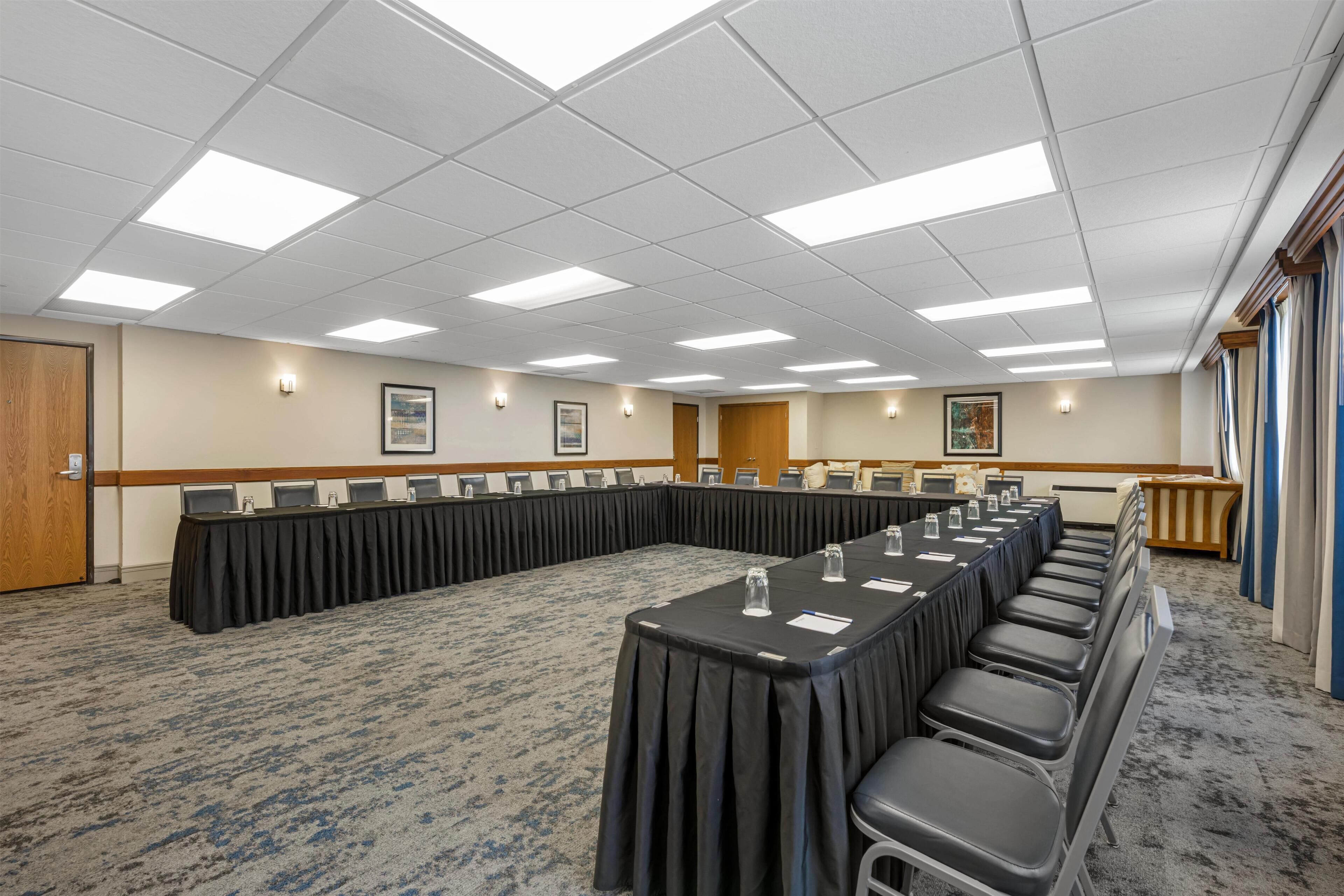 A conference room with a long table, chairs, and a carpeted floor.