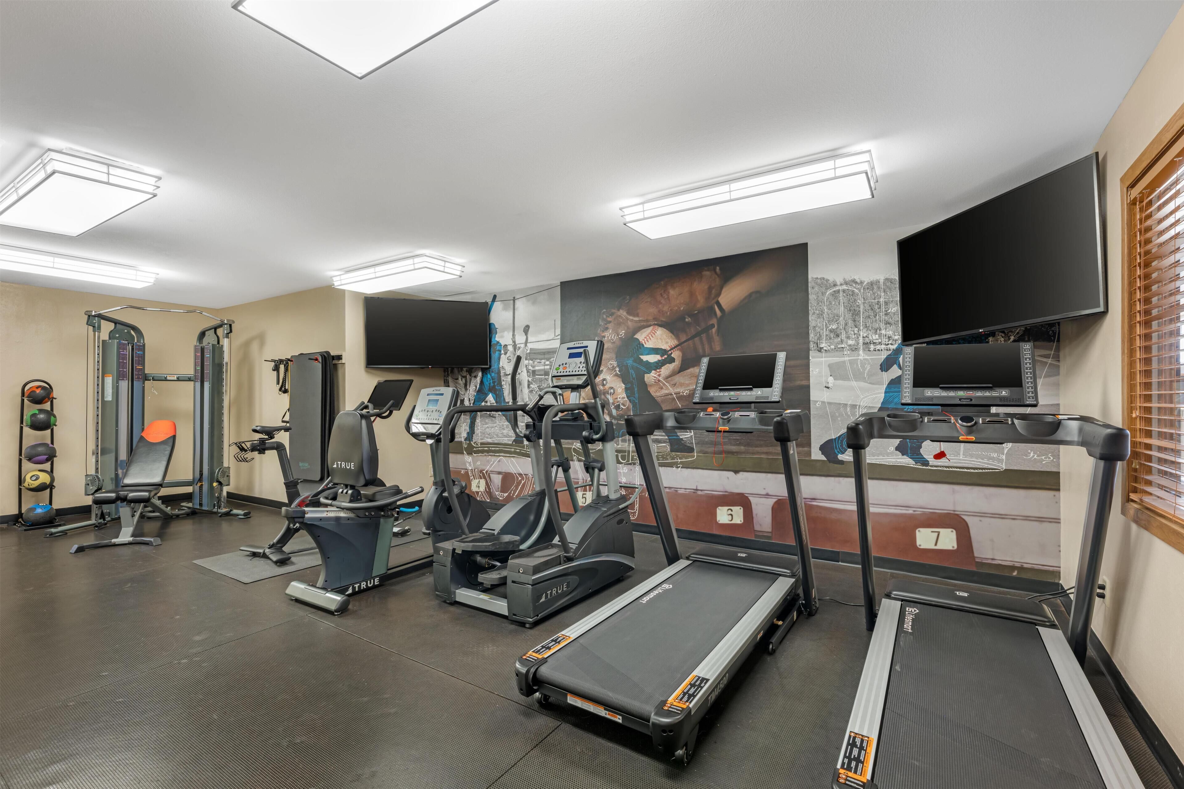 A gym with treadmills, elliptical machines, and weightlifting equipment.
