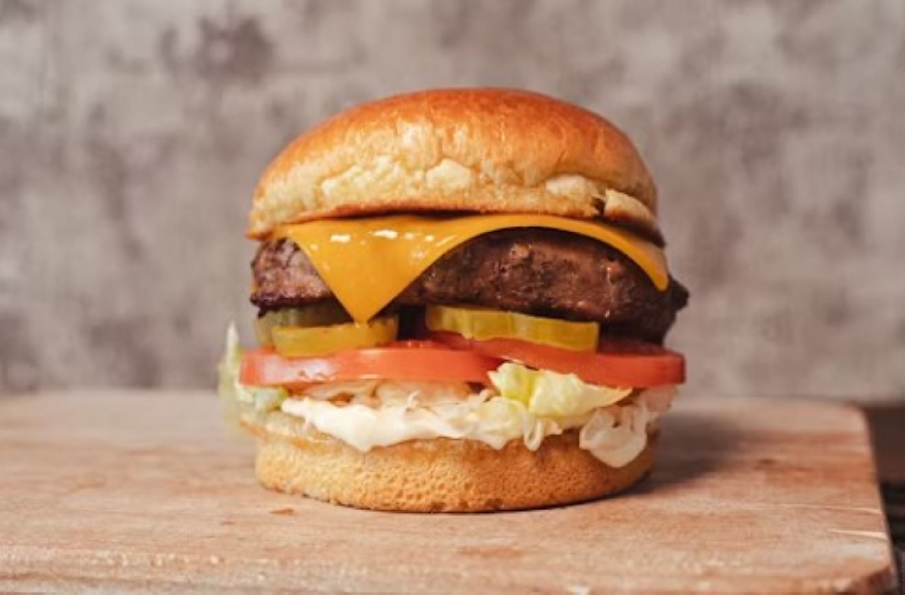Hamburguesa con pan, carne, queso, pepinillos, lechuga y tomate.