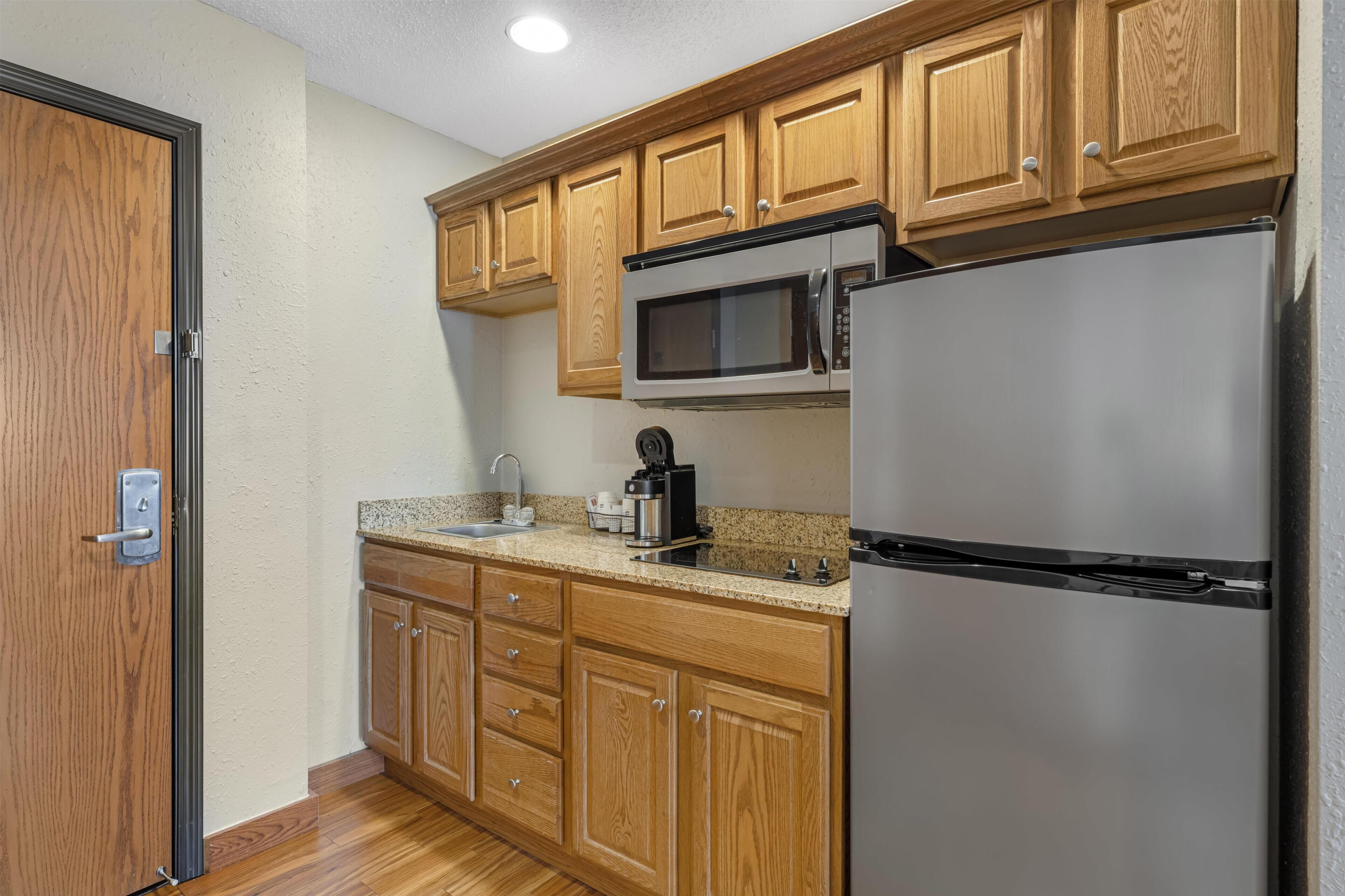 A kitchen with wooden cabinets, a stainless steel refrigerator, a microwave, and a coffee maker.