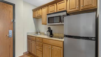 A kitchen with wooden cabinets, a stainless steel refrigerator, a microwave, and a coffee maker.