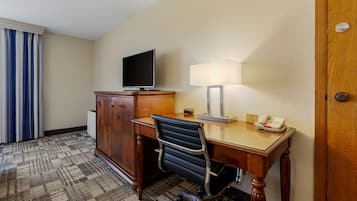 Habitación de hotel con escritorio, silla, televisión, lámpara y teléfono.
