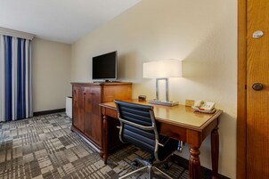 Habitación de hotel con escritorio, silla, televisión, lámpara y teléfono.
