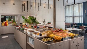Un moderno vestíbulo de hotel con un área de bufé que ofrece una variedad de frutas y bebidas.