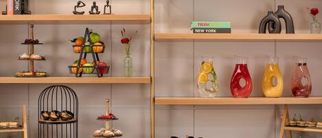 A display of food items on shelves, including fruits, pastries, and drinks.