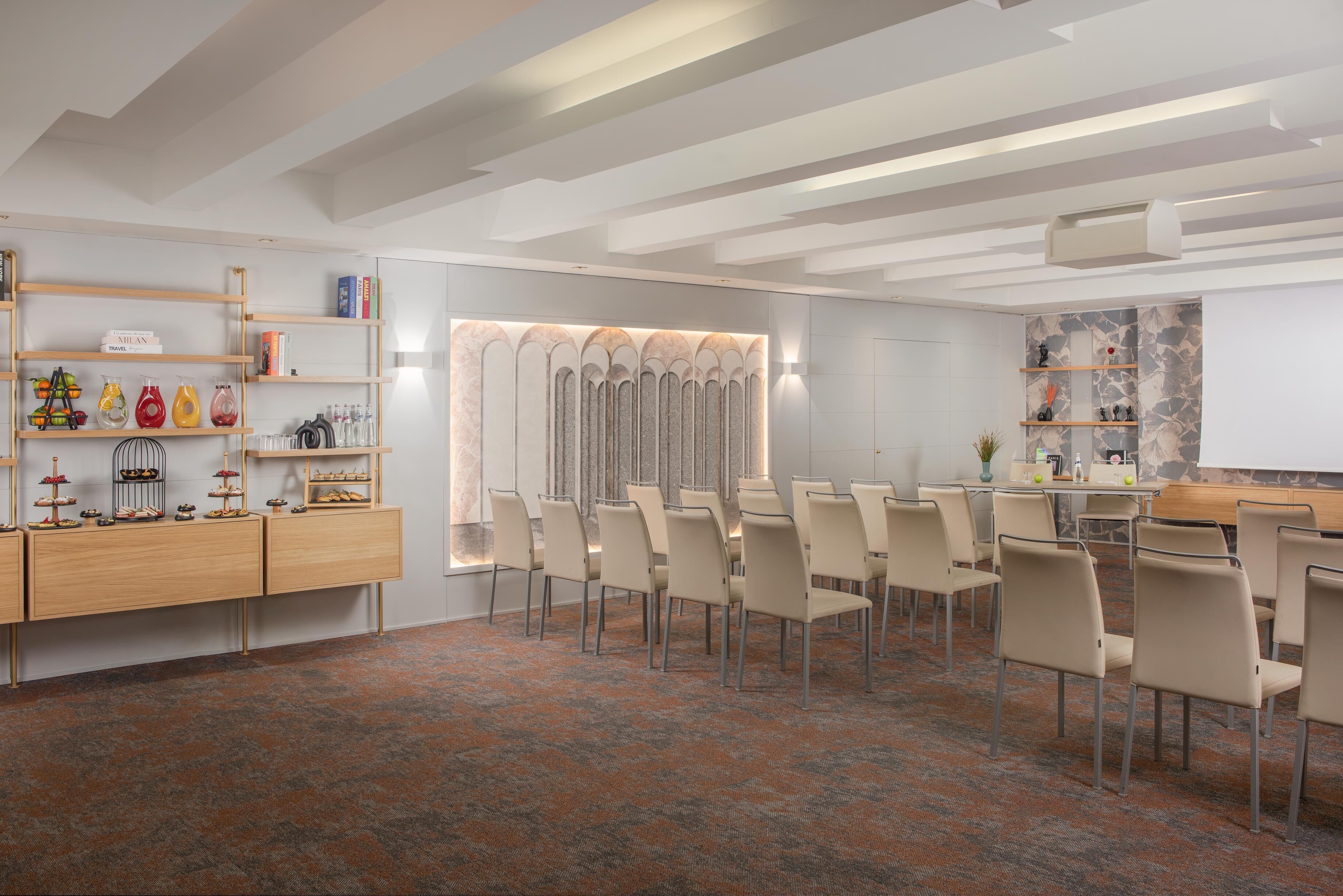 Un salón de conferencias con una larga mesa, sillas, una pizarra y una pared decorativa con un diseño estampado.