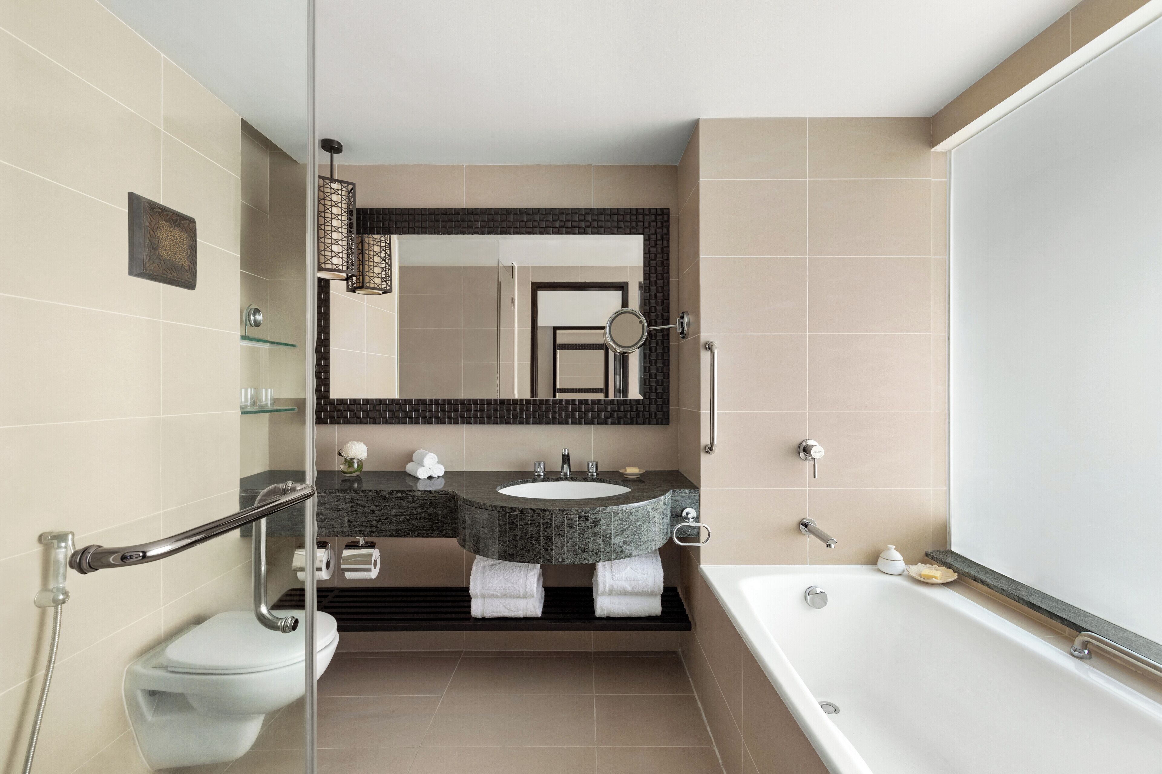 Un baño moderno con cabina de ducha de vidrio, tocador doble, espejo grande y bañera independiente.