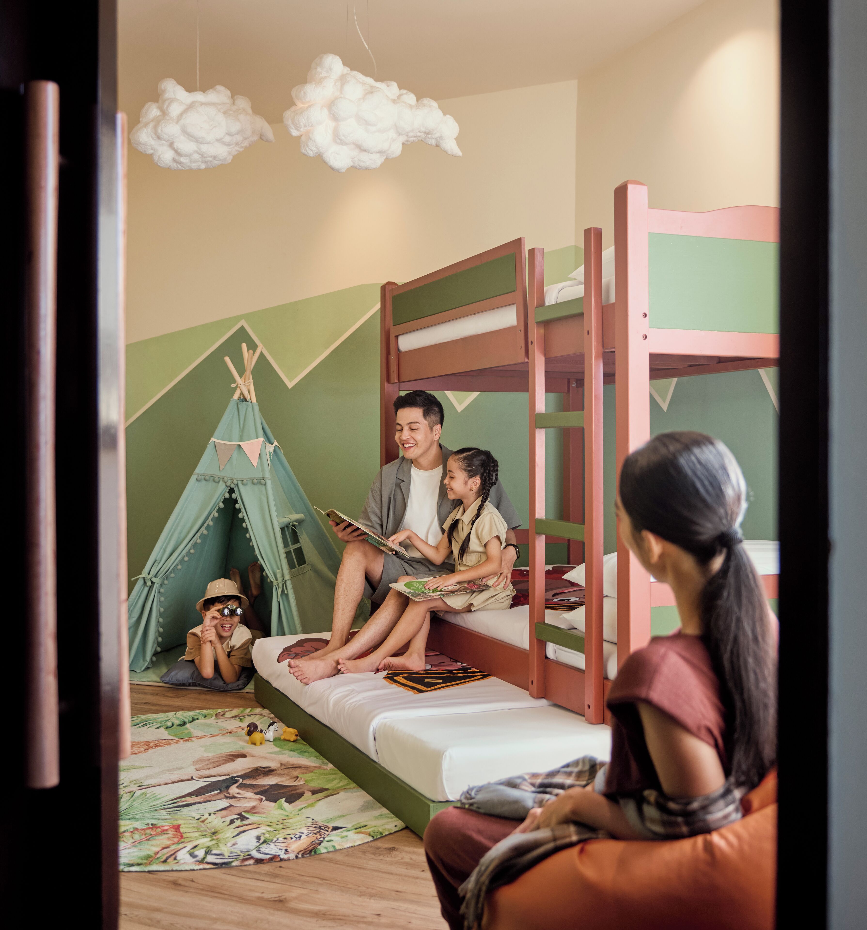 A bunk bed room with a green wall, a tent, and a person reading a book.