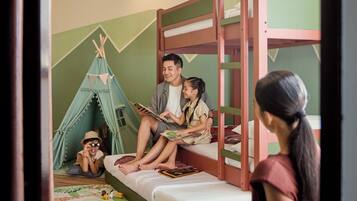 A bunk bed room with a green wall, a tent, and a person reading a book.