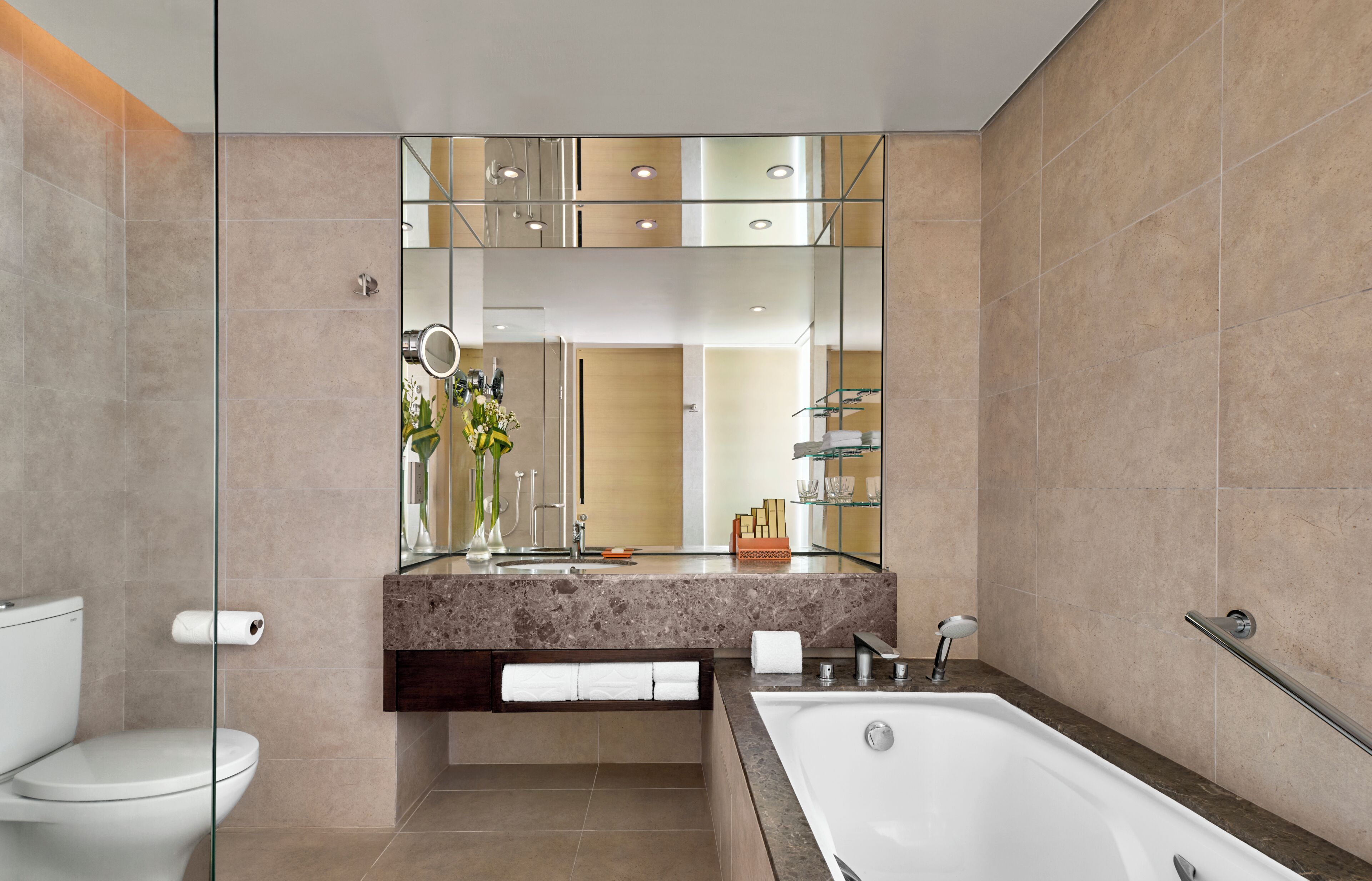 Une salle de bain moderne avec une douche à parois de verre, un grand miroir, une baignoire et des toilettes.