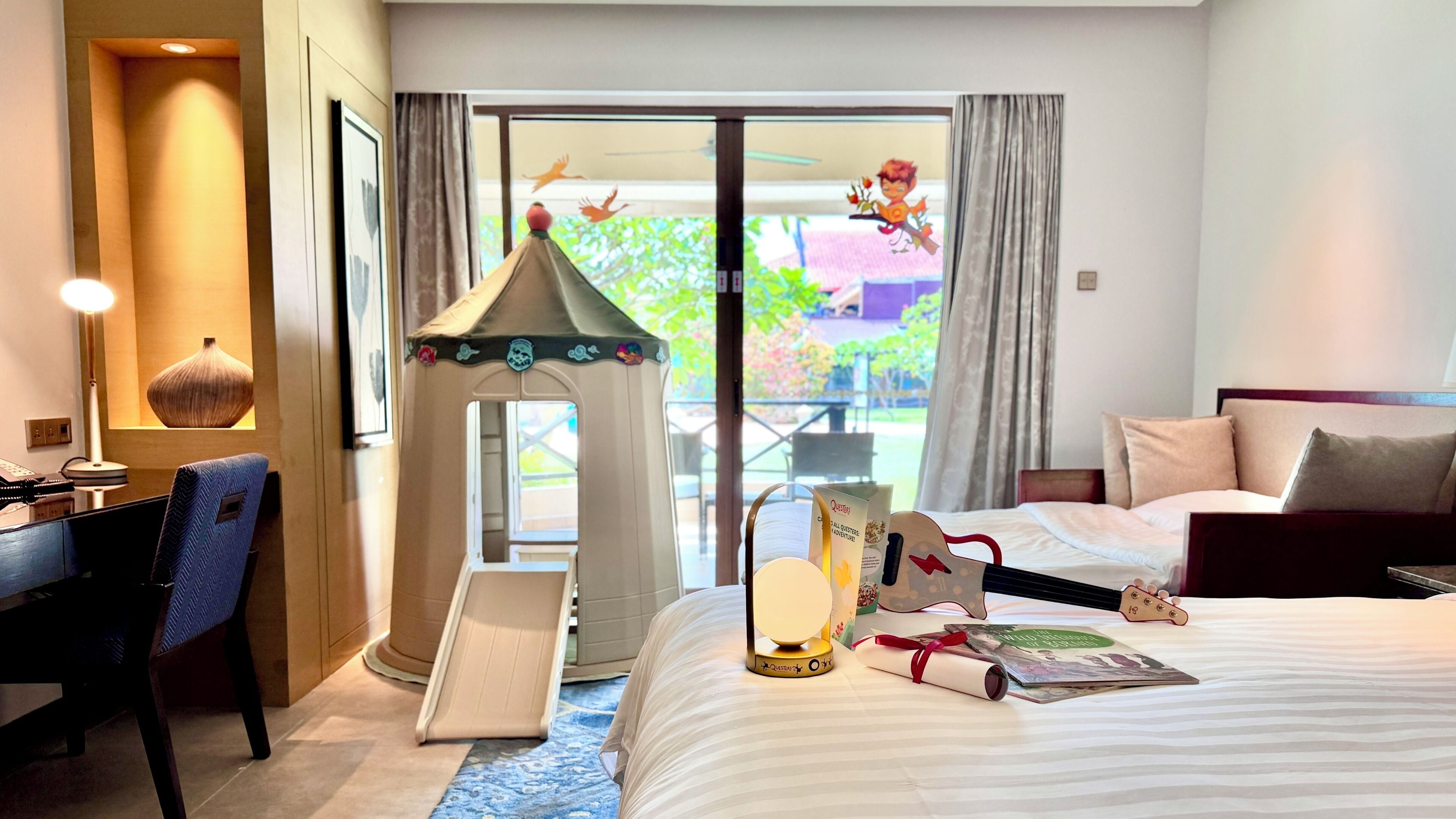 Une chambre d’hôtel équipée d’un lit, d’un bureau, d’une chaise et d’une petite tente de jeu.