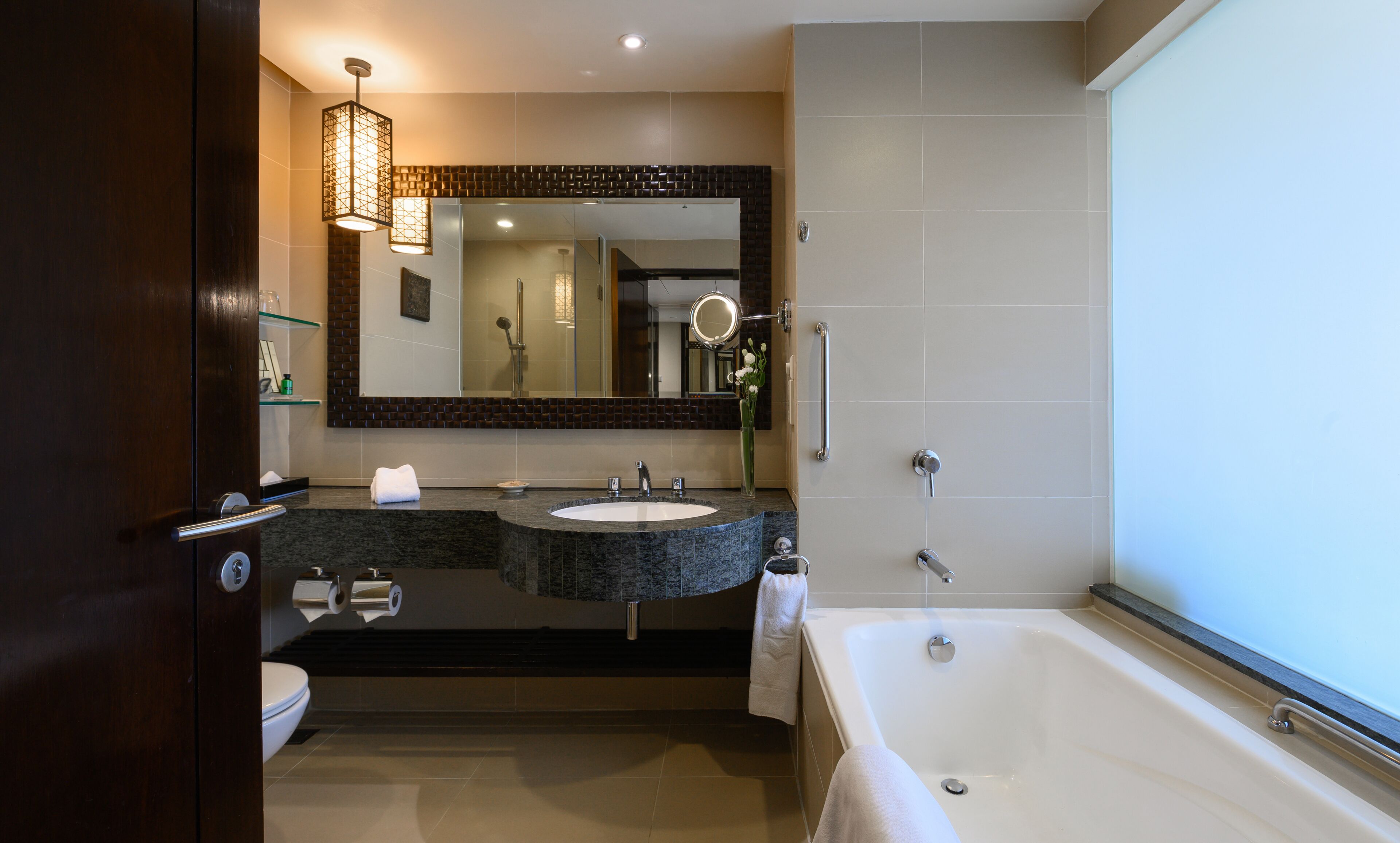 A modern bathroom with a large bathtub, two sinks, a vanity, and a mirror.