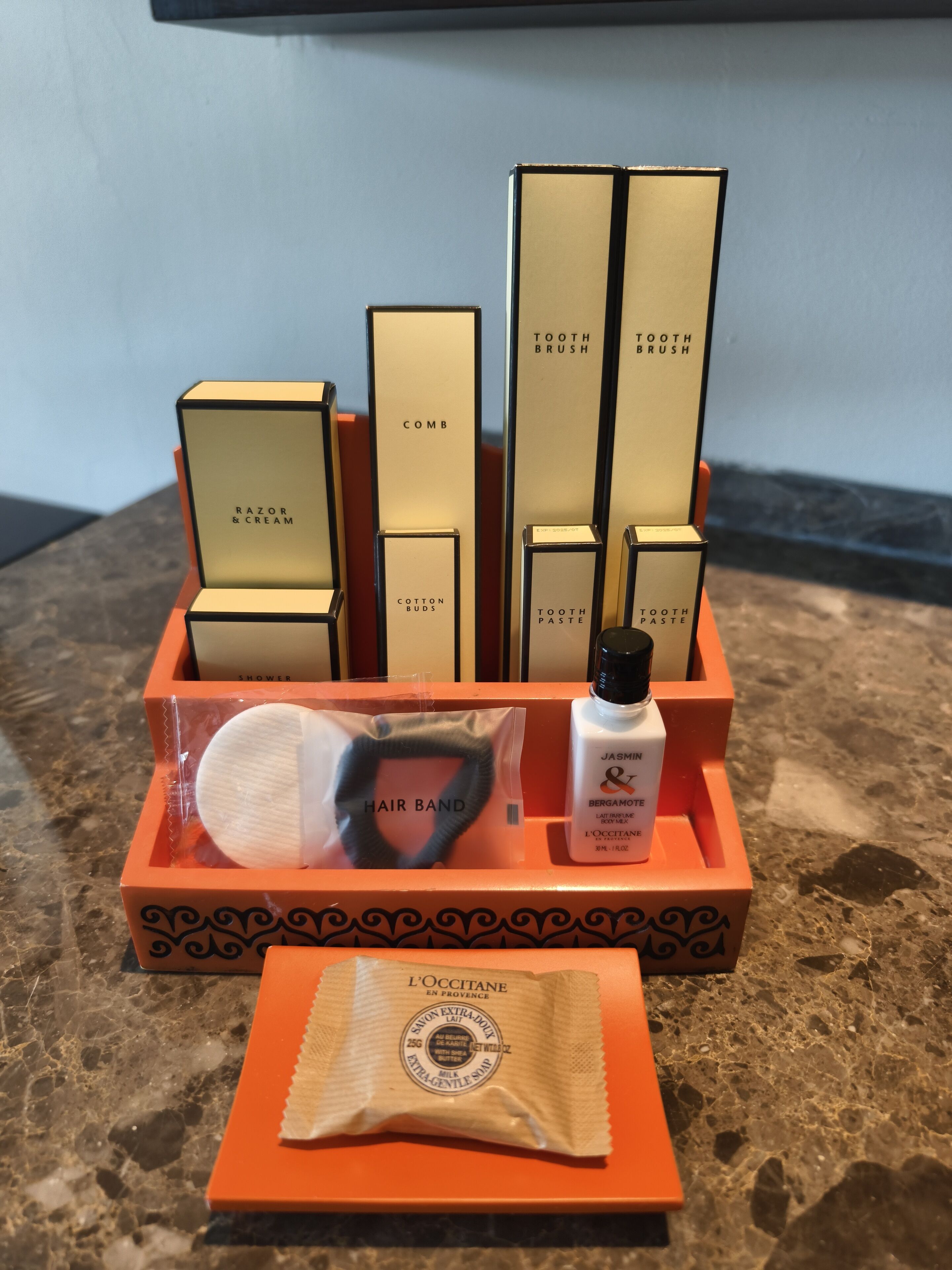 A set of toiletries in a tray, including a hair band, a bottle of jasmine & bergamot lotion, and a comb.