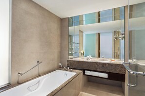 Een aparte badkuip en douche, pantoffels, handdoeken