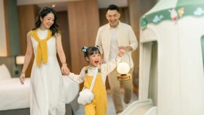 Una familia pasea por el vestíbulo de un hotel, con un niño sosteniendo un farol.