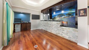 A modern kitchen with a stone backsplash, wooden cabinets, and a built-in island with a sink. - Best Western Post Oak Inn (Burnet)